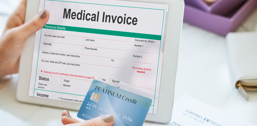 Person holding a medical invoice and blue credit card for healthcare accounts receivable payment